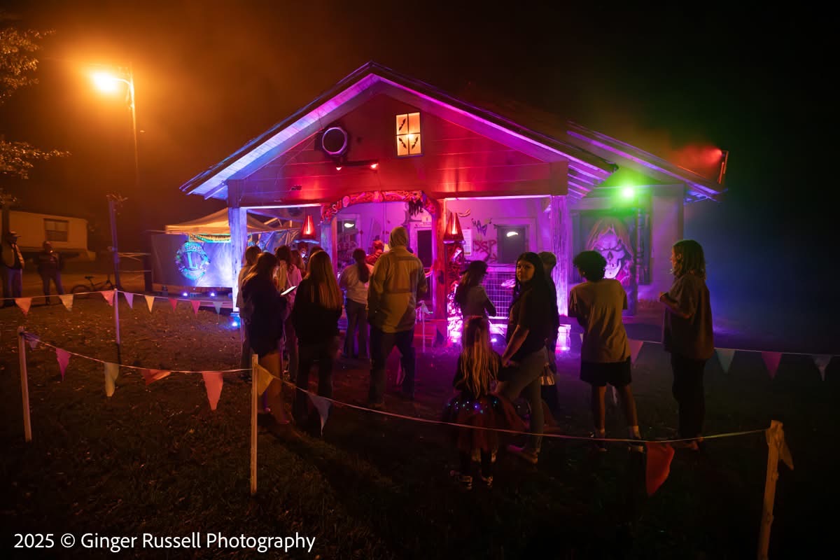 A crowd of visitors queued at the haunted house's lit entrance at night